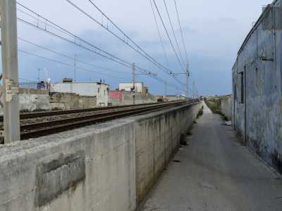 Strada Zuccararo incontra i binari e devia verso destra costeggiata da un muretto